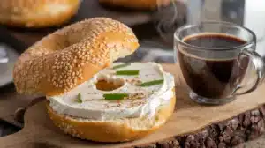 New York-style bagel with cream cheese, chives, and everything seasoning on a wooden board