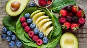 Plated alkaline superfood recipe with avocado slices, spinach, and mixed berries on a wooden background