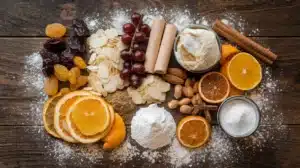 Essential ingredients for Stollen: dried fruits, nuts, marzipan, spices, and powdered sugar on a wooden surface