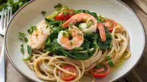 A plate of whole-grain spaghetti with spinach, cherry tomatoes, and grilled shrimp